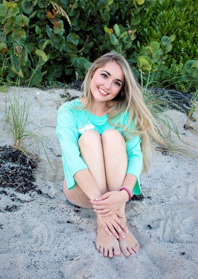 微笑的女孩坐在沙滩白天

